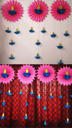 pink and blue paper flowers are hanging from the side of a red curtain in front of a white wall