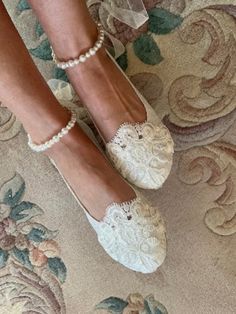 a close up of a person's feet wearing white shoes and pearl bracelets