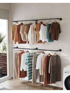 clothes are hanging on the rail in front of a washing machine