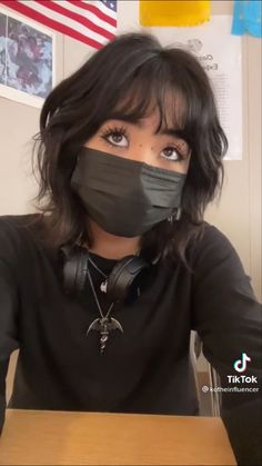 a woman with headphones on wearing a black mask