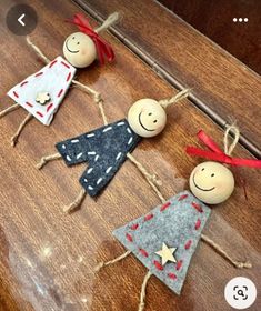 three wooden dolls are sitting on a table with red ribbon around their necks and eyes