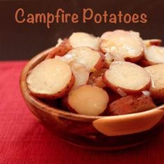 a wooden bowl filled with potatoes sitting on top of a red cloth