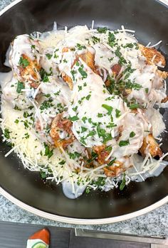 a skillet filled with chicken and cheese covered in grated parmesan sprinkles