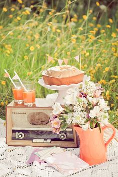 a table topped with an old fashioned radio next to a cake and cup filled with orange juice