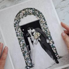 two hands holding an open photo frame with a wedding couple in front of the door