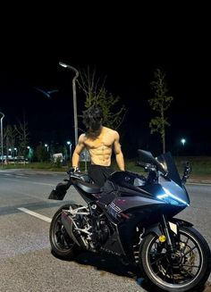 a shirtless man standing next to a motorcycle on the street at night with no shirt