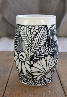 a black and white cup sitting on top of a wooden table