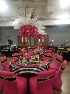 a banquet room set up with pink chairs and black table cloths, centerpieces