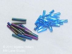 several small blue and purple beads on a white surface