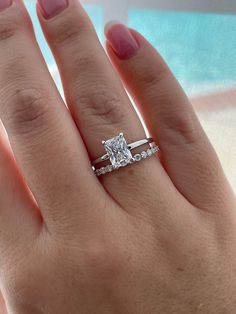 a woman's hand with a diamond ring on top of her finger and an engagement band