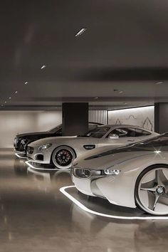 three cars in a showroom with lights on the floor and one car is silver