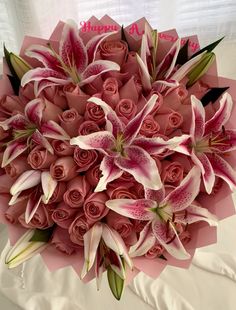 a bouquet of pink roses and lilies on a bed