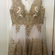 a dress hanging on a door with gold sequins and beads all over it