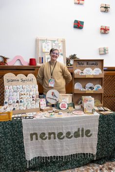 a man standing behind a table covered with lots of items