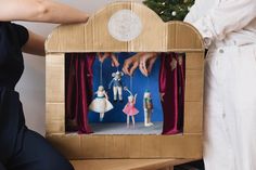 two people are playing with toys in a cardboard box that is being held up by someone's hands