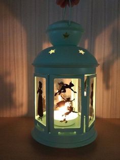 a green lantern with figurines in it sitting on a table next to a wall