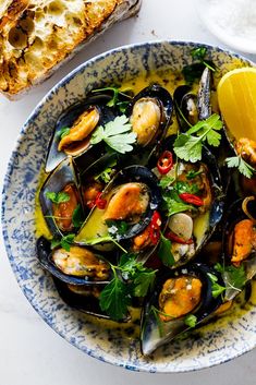 a bowl filled with mussels and garnished with parsley next to bread