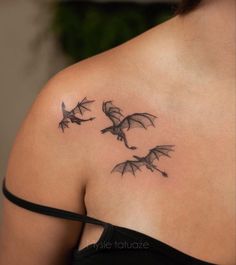 a woman's back shoulder tattoo with three bats flying in the sky above her