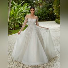 a woman in a white wedding dress standing on a tile floor with palm trees behind her