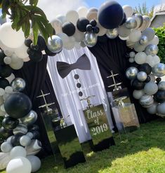 an arch decorated with balloons and black and white decorations