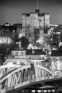 black and white photograph of an old city at night with a bridge over the river