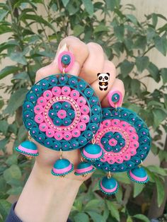 a person holding two colorful earrings in their hand