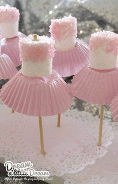 pink and white cupcakes on top of small wooden sticks with marshmallow tops