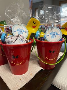 red buckets filled with baby items on top of a table next to plastic cups