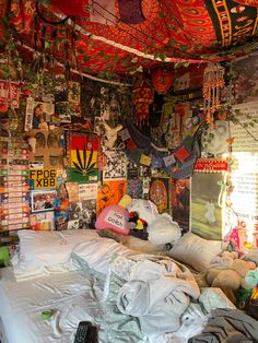 an unmade bed in a room with lots of posters on the walls and ceiling