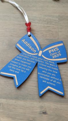 a blue ornament hanging from a string on top of a wooden table with a red ribbon