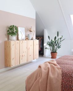 a bedroom with a bed, plant and dresser