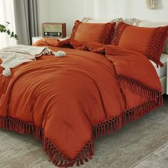 an orange comforter with tassels on it