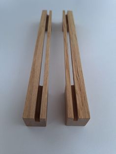 two pieces of wood sitting next to each other on a white surface with one piece missing