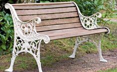 a wooden and white park bench sitting in the grass