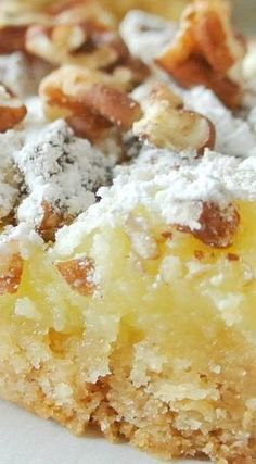 a close up of a piece of cake on a plate with powdered sugar and nuts