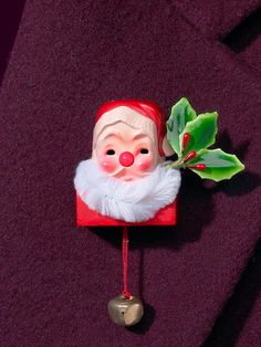 a christmas decoration with a santa clause head and holly leaves on it's side