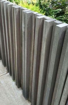 the wooden fence is lined up against the concrete flooring and plants in the background