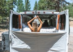 a woman sitting in the back of a truck with her hands up to her head