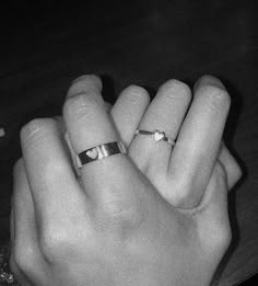 two hands holding each other with wedding rings on their fingers and one has an engagement ring in the middle