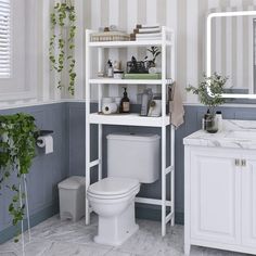 a white toilet sitting under a bathroom mirror next to a shelf filled with towels and other items