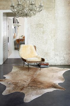 a living room area with a chair, rug and chandelier hanging from the ceiling