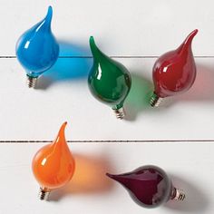 four colorful light bulbs sitting on top of a white table