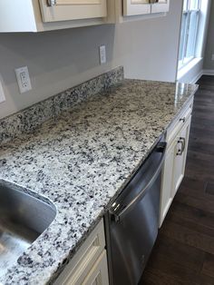 a granite counter top in a kitchen with stainless steel dishwasher and double sink