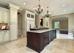 a large kitchen with an island and chandelier hanging from the ceiling over it