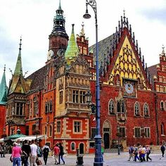 people are walking around in front of an old building with many spires on it