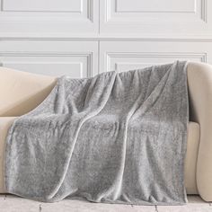 a couch with a blanket on top of it in front of a white paneled wall