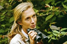 a woman with long blonde hair looking into the distance while holding a pair of binoculars