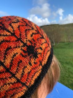 a close up of a person wearing a knitted hat with an orange and black design