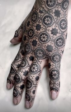 a person's hand with black and white tattoos on it, showing the intricate design