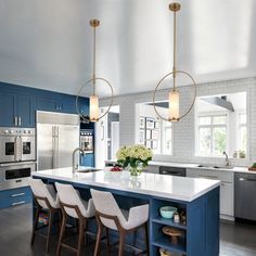 a large kitchen with blue cabinets and white counter tops, an island in the middle